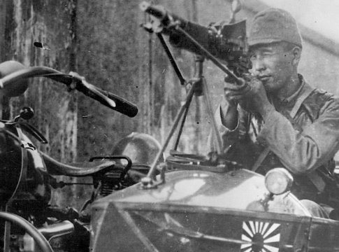 In September 1937, a Japanese soldier aims his machine gun menacingly down a Shanghai street.