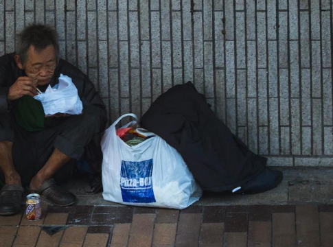 A man sits against the wall in Hong Kong. Photo credit: Jimmy Chan / pexels.com.