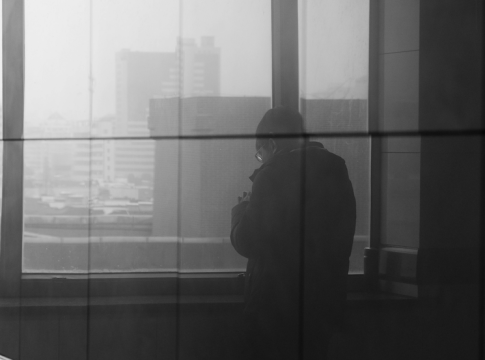 Lonely figure in an urban window with reflection. Photo by Jenkin Shen / pexels.com.