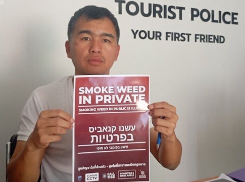 Tourist Police office D'Tom Tomarito holds a sign with instructions in Hebrew on how to behave for Israeli tourists to Pai, Thailand.