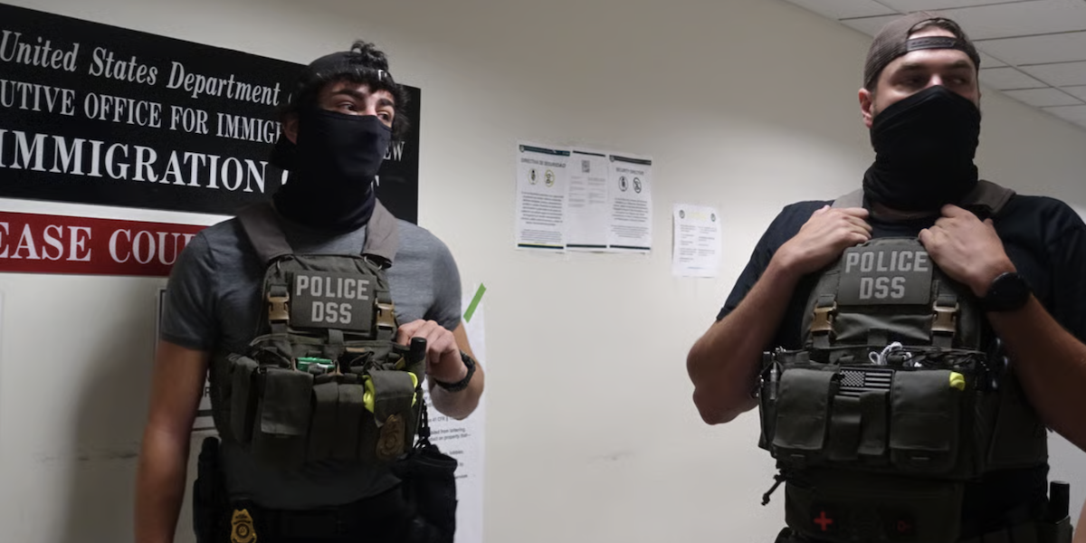 Masked federal agents wait in the hallway outside of mandatory immigration court appearances at the 26 Federal Plaza building in New York City.