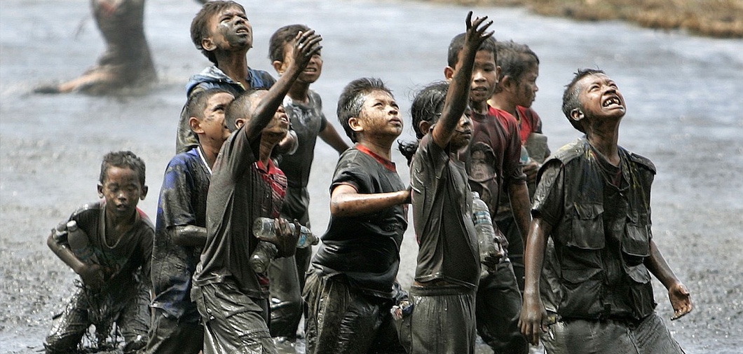 Refugee children try to catch relief goods tossed from an Australian military helicopter in a rice paddy on the outskirts of Banda Aceh, Indonesia, in January 2005. Aceh was hardest-hit by the Dec. 26, 2004, quake-spawned tsunami that killed more than 115,200 people in the northernmost province on Sumatra Island. Across Southeast Asia, nearly a quarter-million people were killed by the tsunami.
